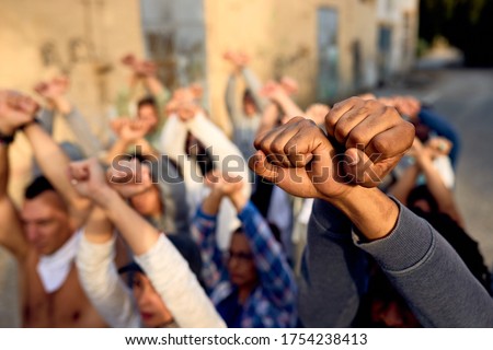 Close-up of large group of protesters with clenched fists above their heads on public demonstrations.  Royalty-Free Stock Photo #1754238413