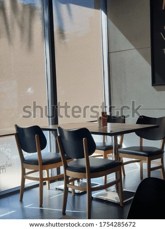 Empty chairs in a room with morning light came in through glass window. Table and seats indoor has a modern design style. Nobody in the picture.  