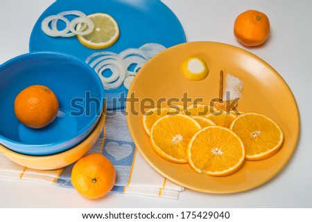 Pictures put from thin slices of onions, orange and lemon on blue and yellow plates -  sea at sunset with ship and sun in clouds.