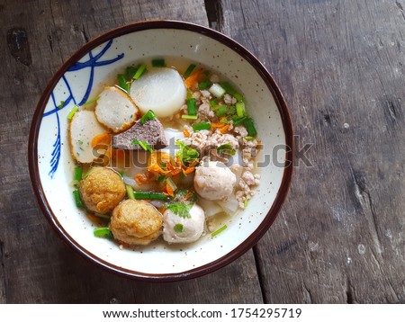 Clear soup noodles with fish ball and minced pork (Tom Yum Noodles) on wooden background. Thai foods. Asian food concept.Soft focus,Select focus Royalty-Free Stock Photo #1754295719