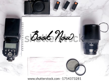 Flatlay of camera gear on marble table with sketch book written book now. Photographer and videographer among occupation that been affected during Covid-19.