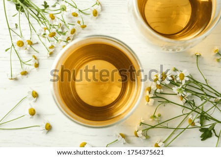 Flat lay composition with tea and chamomile flowers on white wooden table