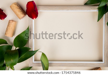 close-up view of frame with corks on white background decorated with leaves and flower petals with copy space