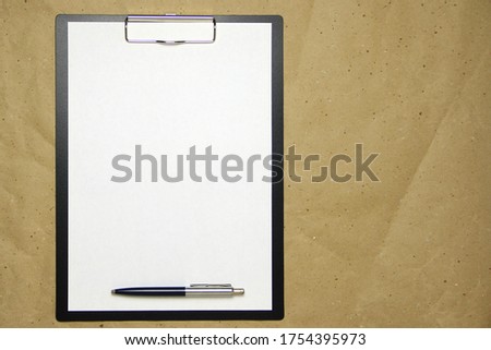 A tablet with a white sheet of A4 format with pen on a beige craft paper. Concept of analysis, study, attentive work. Stock photo with empty place for your text and design.