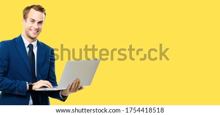 Wide composition picture - confident businessman in blue confident suit, working with laptop, isolated over yellow color background. Handsome man at studio concept picture. Copy space.