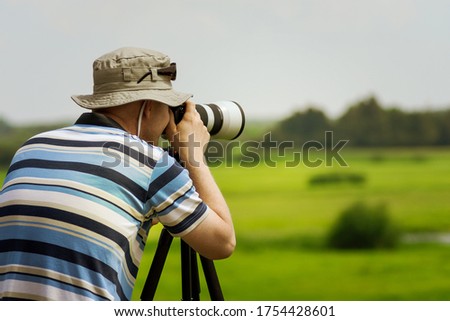 Man in a hat taking a picture at summer. Place for text.