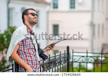 People Traveling. Portrait of Smiling Relaxed Caucasian Male Traveller With Photocamera. Looking For Destination Using City Map.Horizontal Shoot