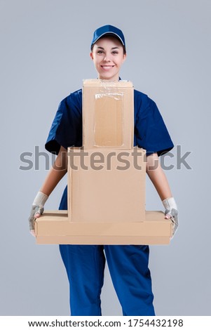 Delivery Services Ideas. Portrait of Positive Caucasian Female Messenger With Variety of Carton Boxes. Against Gray Background. Vertical Image
