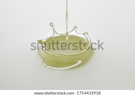 Dripping colorless oil on white background. Royalty-Free Stock Photo #1754432918