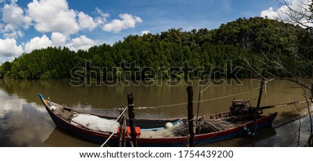 The turquoise river pier, which is a waterway, has a local fishing boat parked on both sides of the canal, surrounded by lush mangroves and completely adoied in the tropics of Asia.