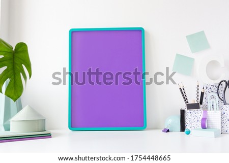 Poster frame mockup on stylish desk with purple elements.