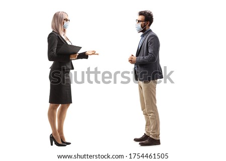 Full length profile shot of a businesswoman talking to a male colleague and wearing protective face masks isolated on white background