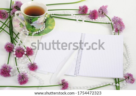 beautiful picture decorated with pink flowers with a cup of tea pearls with a pen for writing text greetings