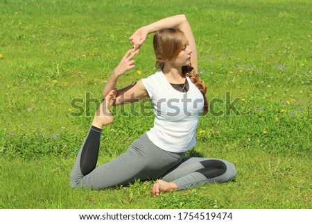 Young woman of European appearance does yoga in summer nature. Woman sitting in pigeon pose, eka pada rajakapotasana. High quality photo for web and print with empty space for text and design.