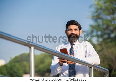 A portrait of businessman with smartphone standing outside the office