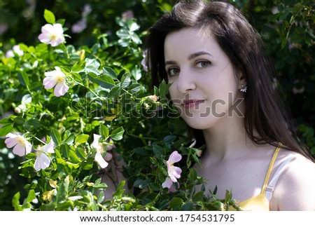 Attractive young brunette woman in yellow t-shirt. in a bush full of floweers. copy space. High quality photo