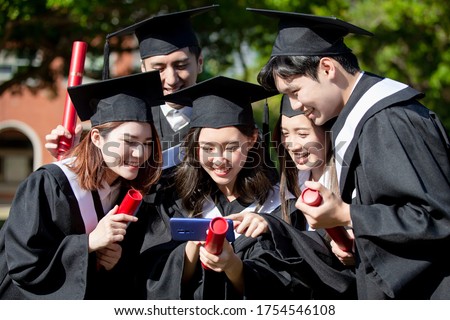 group happy graduates students use mobile phone to look pictures together