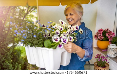 Senior woman taking care of her plants on the balcony 
