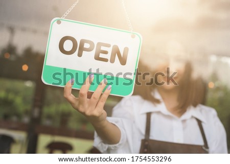 Woman hand open sign board on the door cafe or restaurant hang on door at entrance.