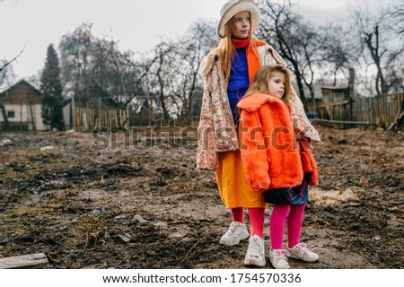 Picture of cute little caucasian sisters with pretty faces in old clothes spend a lot of free time together in the village on the autumn holidays.
