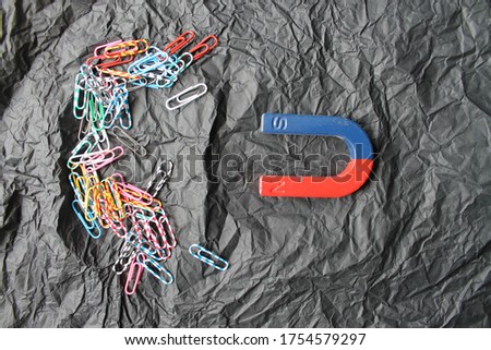 magnet and color paperclips on a black background, close-up
