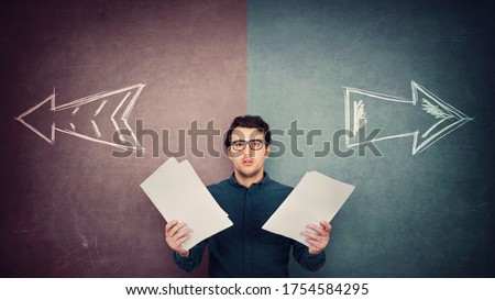 Perplexed businessman has to choose as holds different paper documents in both hands. Selecting the correct financial report, arrows shows left and right sides. Difficult decision, doubt concept. Royalty-Free Stock Photo #1754584295