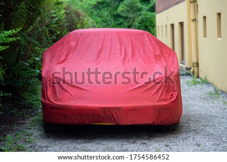 Yellow sport car under red Waterproof Car Cover parked on a gravel road. Royalty-Free Stock Photo #1754586452
