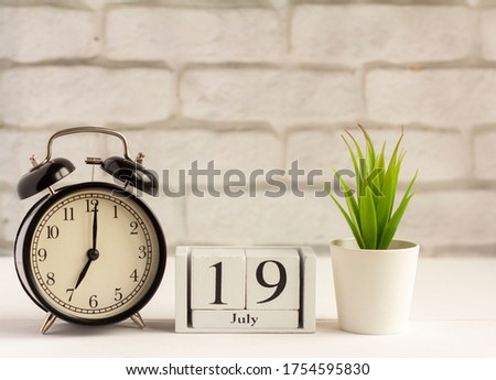July 19.Wooden calendar with date and table clock with bells on the table or shelf. It's July.High summer.