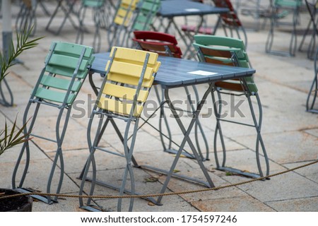 Colorful chairs folded outside the restaurant cafe. With covid-19 restrictions and social distancing - many restaurants are still closed. Royalty-Free Stock Photo #1754597246