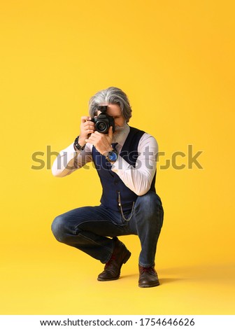 Handsome senior photographer on color background