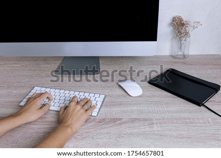 Hands of a young woman writing on a keyboard of a computer in home office