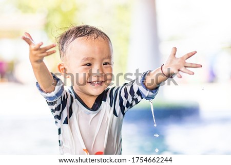 Little adorable boy in swimming suit doing water splash