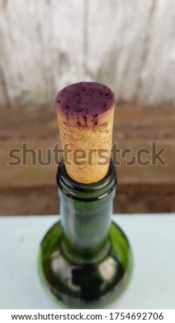 Closeup to purple surface of old wine cork colored by grape wine. Top of wine bottle on blur rustic wooden background with copy space