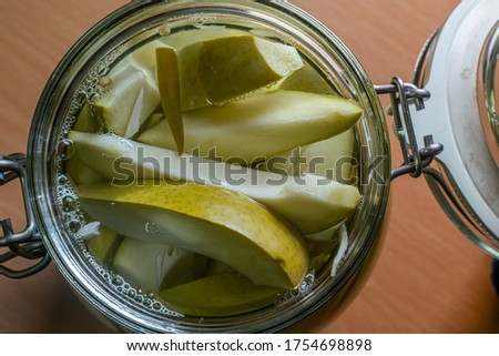 a bunch of fresh salted mango pieces in a glass jar with blurry background