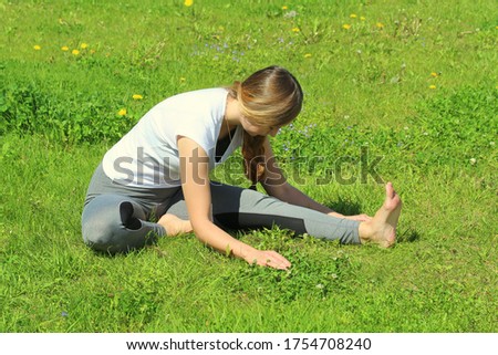 Young woman of European appearance does yoga in summer nature. Woman sitting in mahamudra pose. High quality photo for web and print with empty space for text and design.