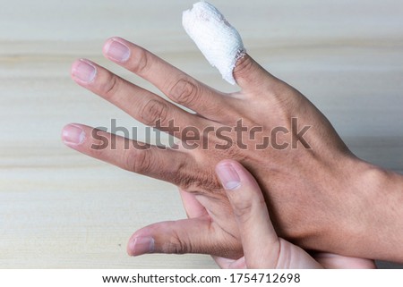 The wrinkled hand with the little finger has to be treated as a wound with a white bandage. On a wooden table with clipping path Royalty-Free Stock Photo #1754712698