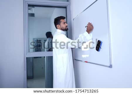 Saudi Arab Man writing on white board using in office 