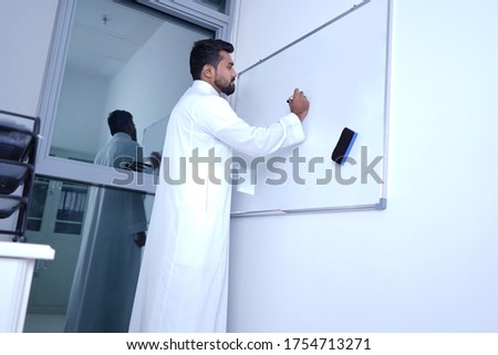 Saudi Arab Man writing on board in office