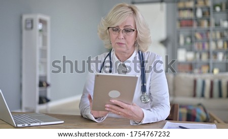 Senior Old Female Doctor Using Tablet for Work