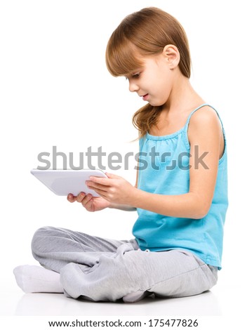 Young girl is using tablet while sitting on floor, isolated over white