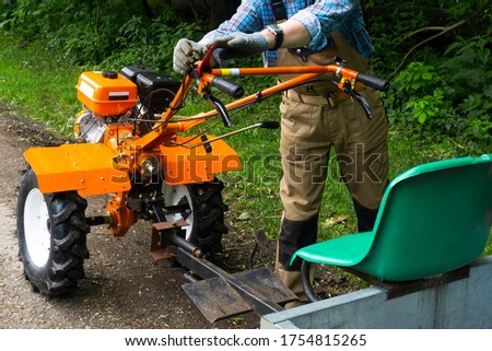 A man adjusts the brake system of a self propelled vehicle made of a motorcycle cultivator Royalty-Free Stock Photo #1754815265