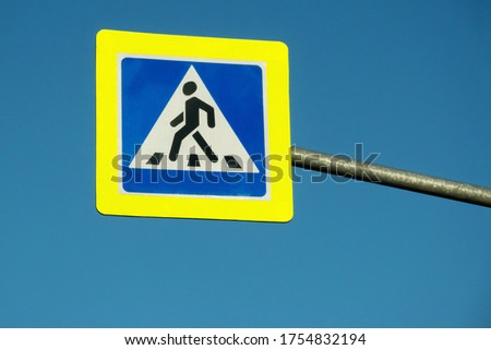 The road sign "pedestrian crossing" is mounted on a high curved stand above the roadway. Copy space.