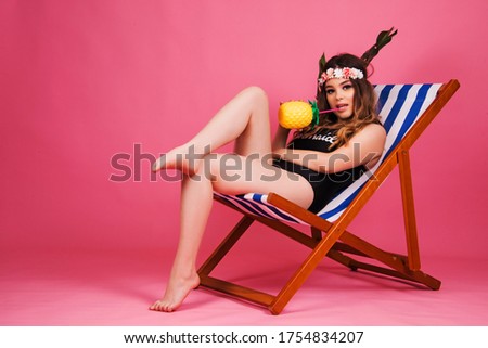 smiling girl in beach chair, wearing swimming suit isolated on pink background, seasonal summertime concept