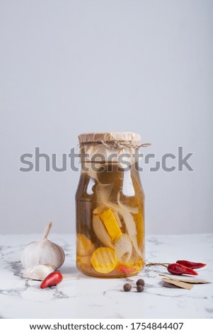 Fermented cucumbers and squash on a table in a glass jar