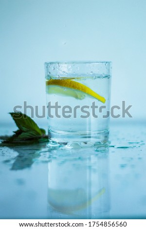 A glass of refreshing water with lemon on a blue background. Heat concept, fresh.