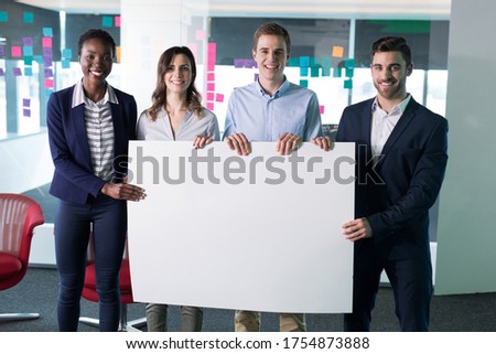 Portrait happy executives holding a blank banner in office