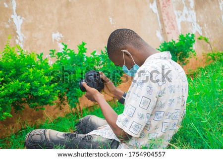 young black man wearing a nose mask and using his camera to snap some pictures
