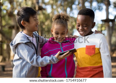 Kids reviewing pictures on mobile phone in park