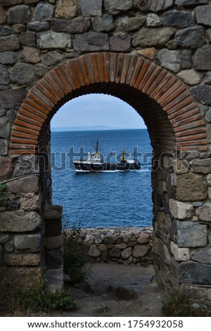 Old fortress in Sozopol and a ship seen sailing through it in the sea. Sozopol is a city in Bulgaria. High quality photo of a ship sailing
