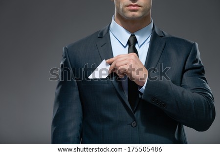 Part of body of man who pulls out white card from the pocket of business suit, copyspace